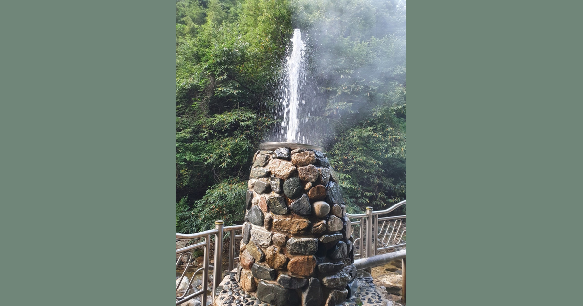 울창한 숲을 배경으로 돌을 쌓아 만든 탑에서 뜨거운 물줄기와 김이 위로 솟구쳐 오르는 모습.