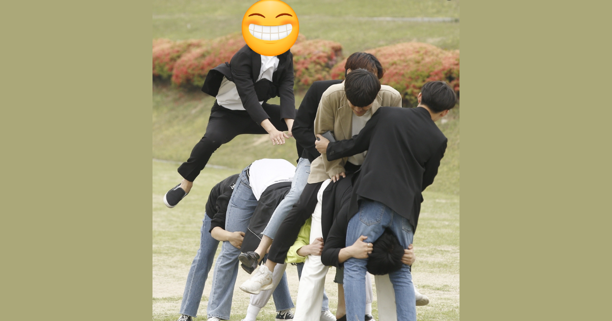 야외 잔디밭에서 여러 명의 남성들이 말뚝박기 놀이를 하며 즐거운 시간을 보내고 있습니다.